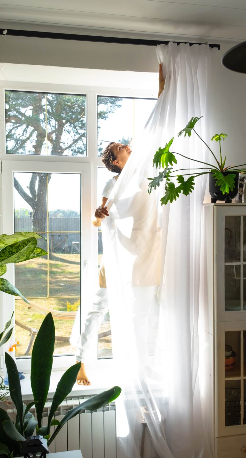 woman-in-apron-hangs-transparent-tulle-curtains 2